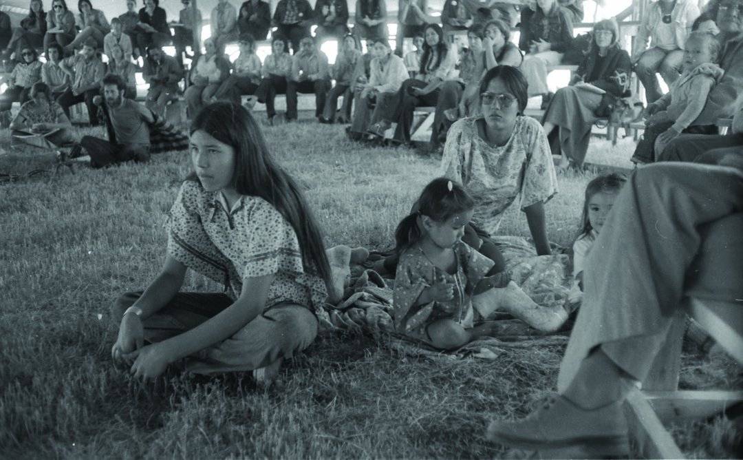 A teenage Marcella Gilbert and others listen at a gathering.