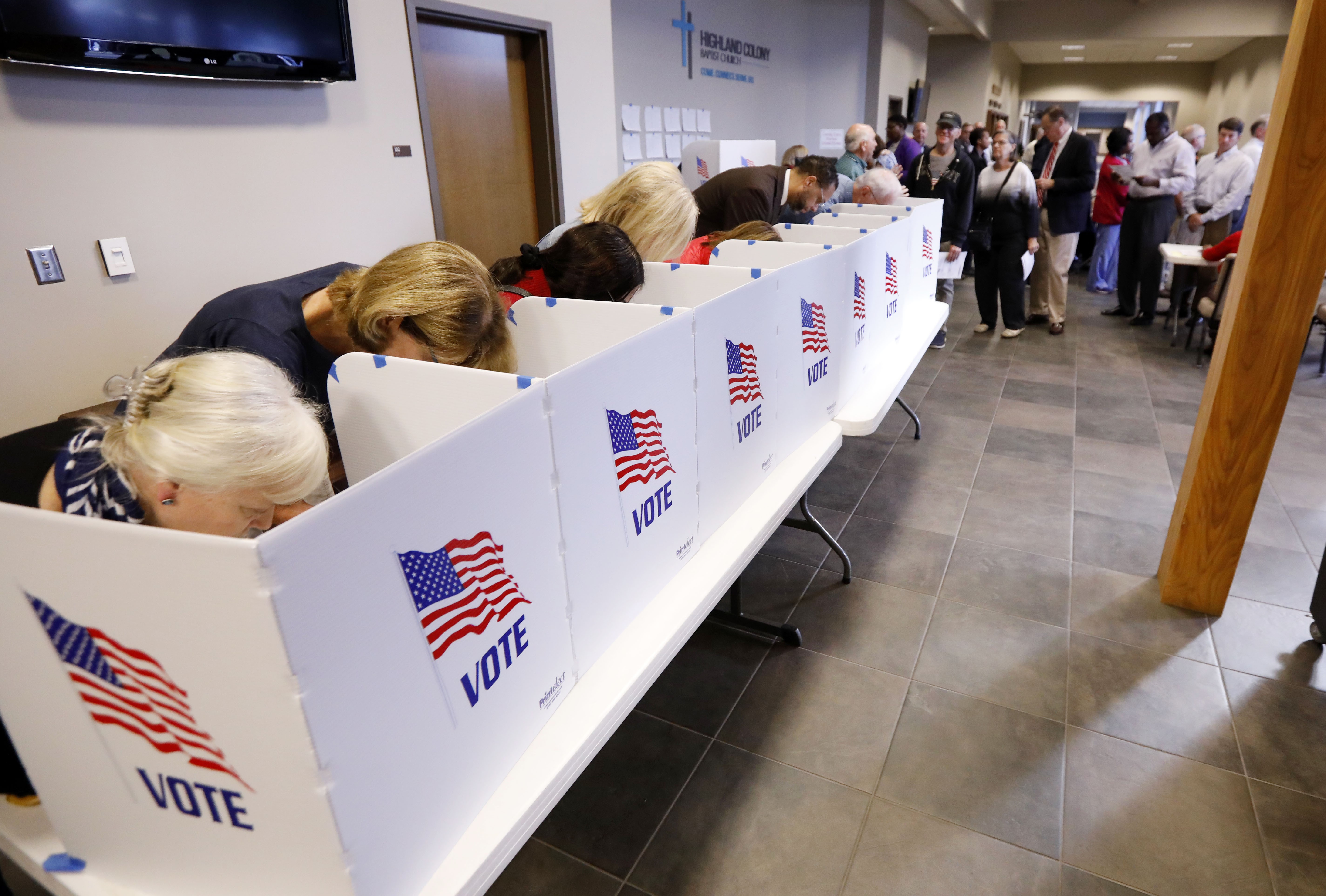 A growing line of voters, right, wait as others fill out their paper ballots in privacy voting booths, Tuesday, Nov. 6, 2018, in Ridgeland, Miss. Voters have a number of races to consider, including judiciary and federal offices and some local issues.