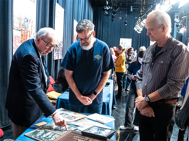Appraiser Ross Kelbaugh, series executive producer Patrick Keegan, and a guest examine a collection of President John F. Kennedy historical objects during the show’s Season 13 taping event in October