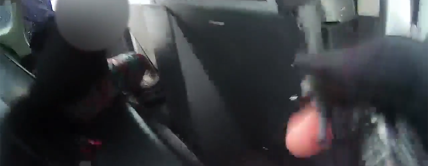 A low-res, censored image of a 9-year-old firl handcuffed in the back of a police car.