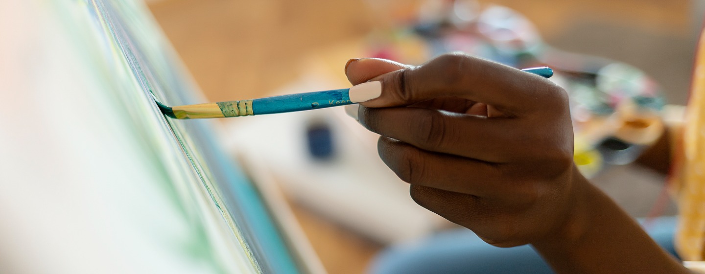 Woman applying a paint brush to a canvas