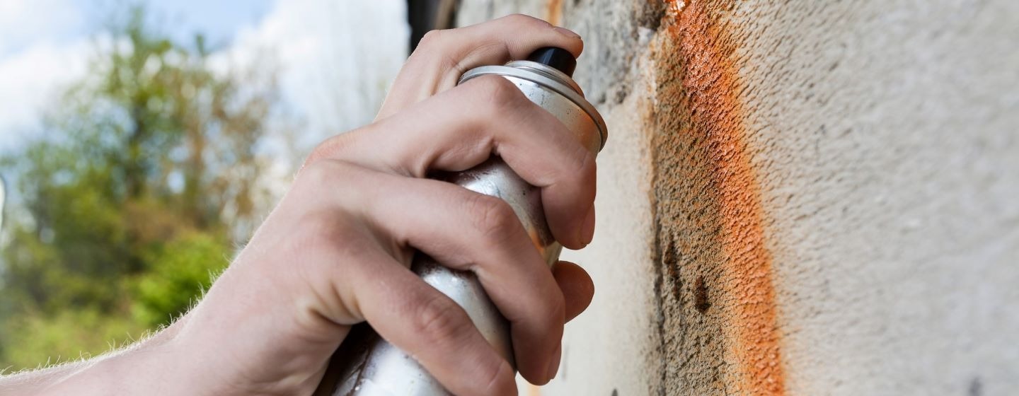 Spray painting a wall with graffiti