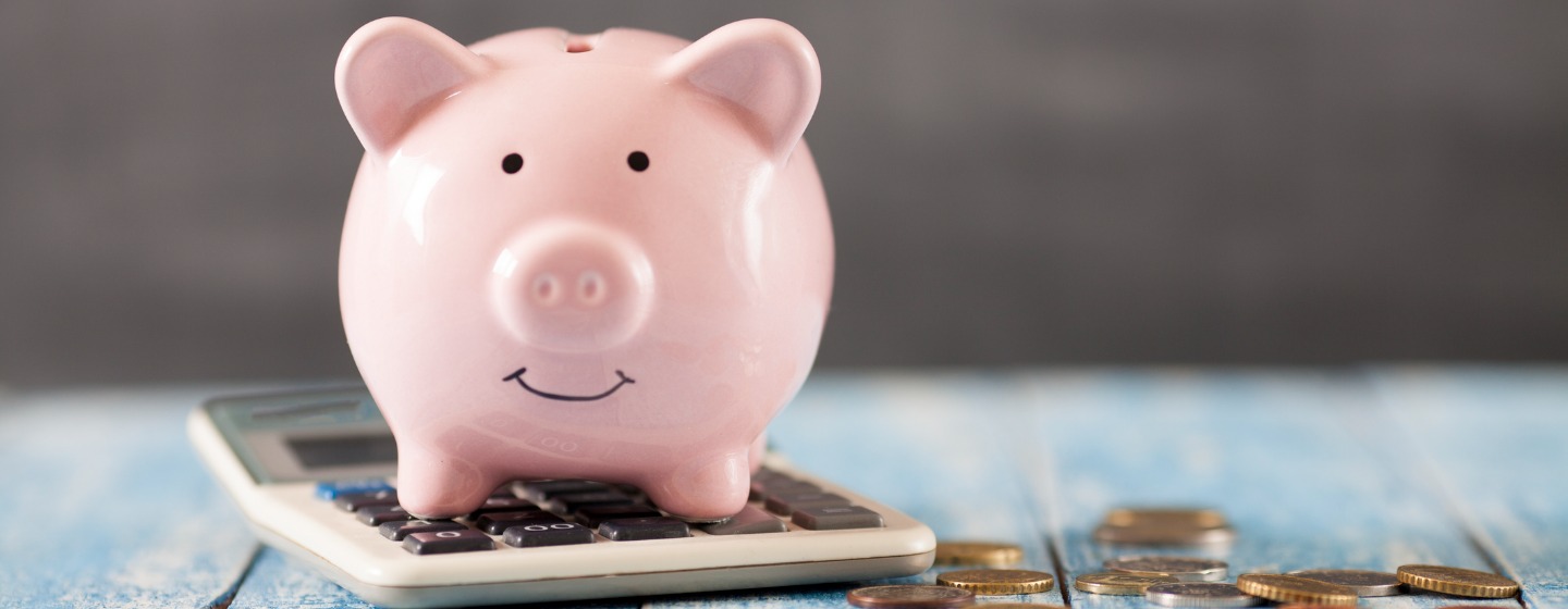 Piggy bank, calculator, and coins on a desk