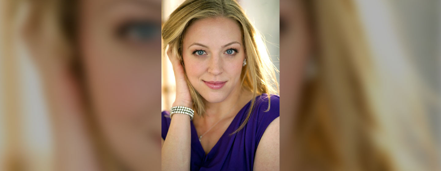 Soprano Emalie Savoy posing for a photo, wearing a purple dress.